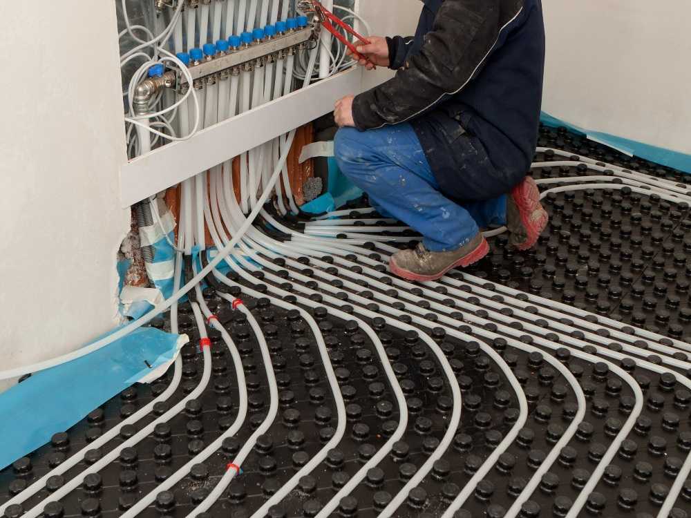 Loodgieter legt vloerverwarming aan en sluit de leidingen aan op de verdeler